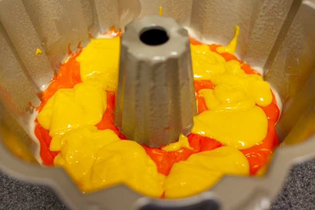 Rainbow Bundt Cake from thelittlekitchen.net Yellow cake batter poured on top of orange cake batter in Bundt cake pan