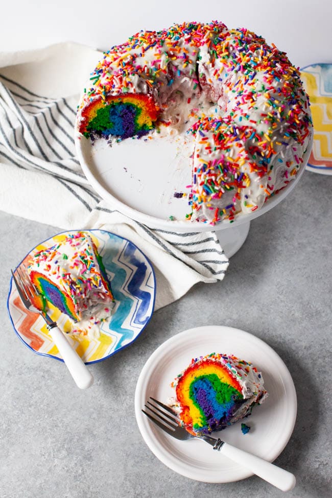 Rainbow Bundt Cake from thelittlekitchen.net Two slices of rainbow cake on two plates with forks next to full tray of cake