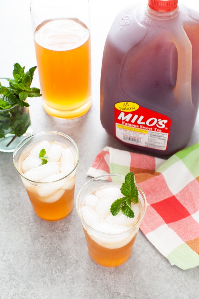 Sweet Tea with Vodka and Lemonade from thelittlekitchen.net glasses with sweet tea vodka and lemonade with jug of Milo's Sweet Tea in the background, glass with fresh mint