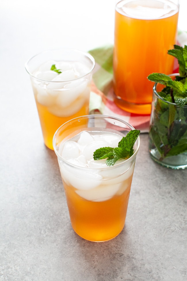 Sweet Tea with Vodka and Lemonade from thelittlekitchen.net glasses with sweet tea vodka and lemonade with fresh mint in a glass on the side and a pitcher of the same drink in the background