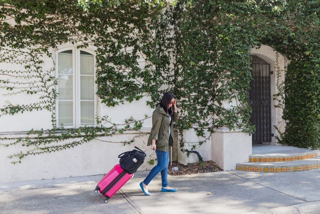 Travel thelittlekitchen.net a woman rolling a suitcase and a carry on bag on the sidewalk