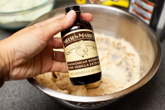 Matcha Cookies from thelittlekitchen.net Hand holding bottle of vanilla extract with mixing bowl in background for Matcha Cookies from thelittlekitchen.net