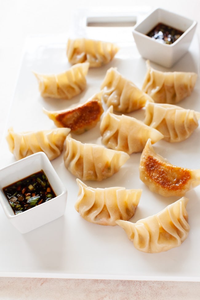 Vegetarian Dumplings from thelittlekitchen.net Vegetarian Dumplings on white serving board with two square cups filled with dipping sauce from thelittlekitchen.net