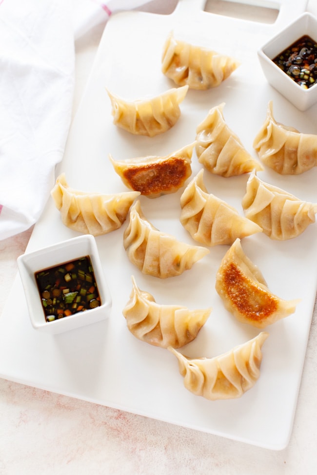 Vegetarian Dumplings from thelittlekitchen.net Vegetarian Dumplings on a white serving board with two square cups filled with dipping sauce from thelittlekitchen.net
