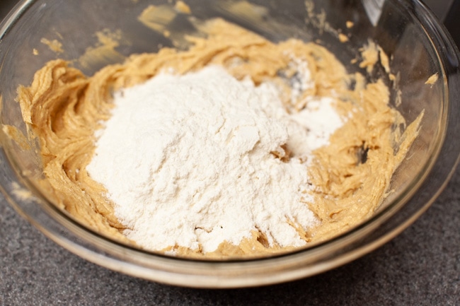 Peanut Butter Blossom Cookies from thelittlekitchen.net Flour being added to the peanut butter blossom cooking dough in a glass bowl.