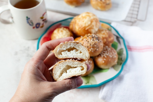 Stuffed Bagel Bites from thelittlekitchen.net a stuffed bagel bite cut in the middle showing the cream cheese inside, a cup of tea in the background along with more stuffed bagel bites