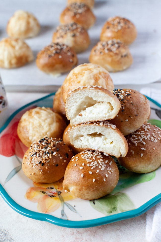 Stuffed Bagel Bites from thelittlekitchen.net a stuffed bagel bite cut in the middle showing the cream cheese inside and in the background along with more stuffed bagel bites