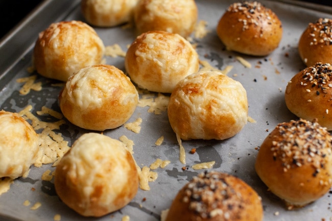 Stuffed Bagel Bites from thelittlekitchen.net stuffed bagel bites with toppings on a parchment paper lined baking sheet right out of the oven