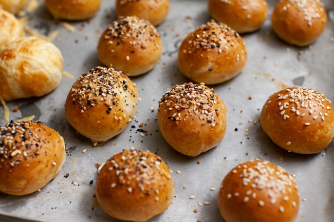 Stuffed Bagel Bites from thelittlekitchen.net stuffed bagel bites with toppings on a parchment paper lined baking sheet right out of the oven