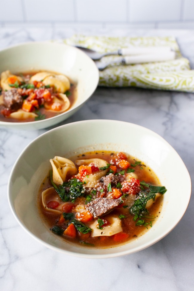 Instant Pot Tortellini Soup from thelittlekitchen.net Two white bowls of Beef Tortellini Soup with two spoons and green napkin in the background.