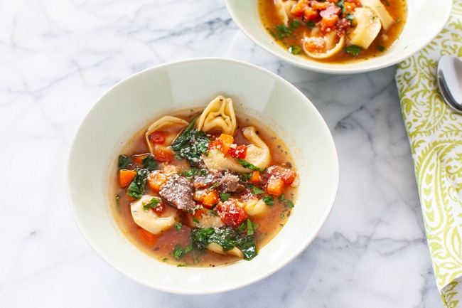 Instant Pot Tortellini Soup from thelittlekitchen.net A white bowl of Beef Tortellini Soup in the center of the picture with a green napkin and spoon in the background.
