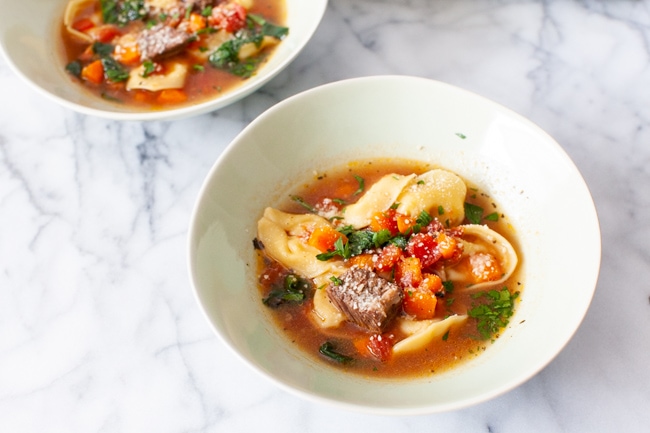 Instant Pot Tortellini Soup from thelittlekitchen.net A white bowl of Beef Tortellini Soup in the center of the picture with another bowl of soup in the background.