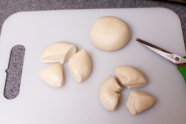 Easy Monkey Bread with Nutella from thelittlekitchen.net cut pieces of yeast rolls on a cutting board with a pair of kitchen shears