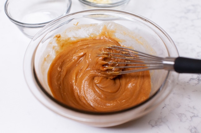 How to Make Peanut Sauce from thelittlekitchen.net almost done making peanut sauce in a glass bowl with a whisk